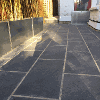 The finished patio with rectangular black/grey granite style paving slabs. The rotten wooden planters were replaced with zinc planters
