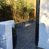 The finished patio with rectangular black/grey granite style paving slabs. The rotten wooden planters were replaced with zinc planters
